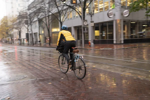 一个骑自行车的人在寒冷潮湿的冬天在潮湿的街上换车 潘宁镜头以模糊的动作 图库照片