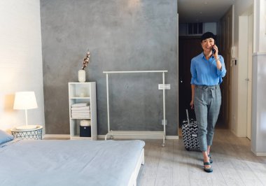 Modern odada dikilen bir kadın telefonda konuşuyor.