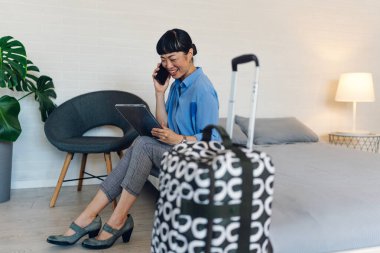 Sandalyede oturan kadın akıllı telefon ve tablet kullanıyor.