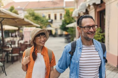 Happy couple walking outdoors along sunny european street