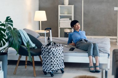 İş kadını modern odadaki bavulun yanında dinleniyor.