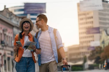 Smiling man and woman exploring city streets during sunny afternoon walk