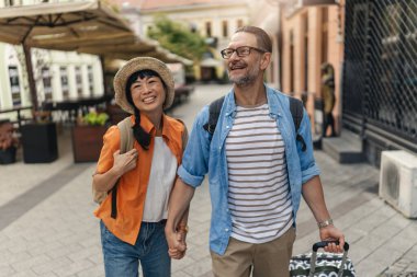 Smiling couple walking outdoors holding hands enjoying sunny day together