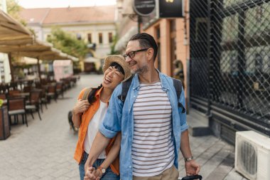 Smiling couple walking outdoors holding hands enjoying city street