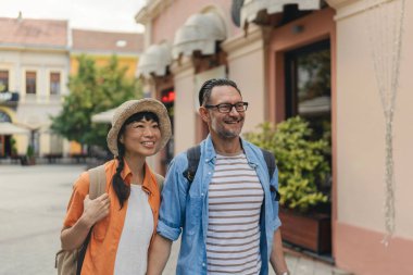Joyful couple walking outdoors enjoying summer vacation together happily