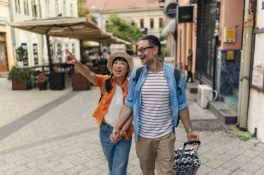 Smiling couple holding hands exploring city street together outdoors