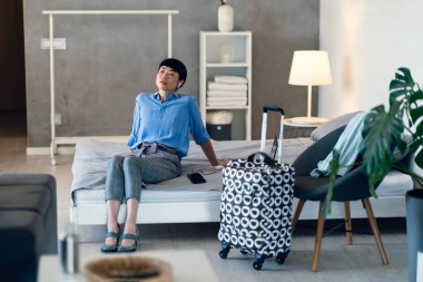 Woman relaxing on bed after arriving at modern hotel room
