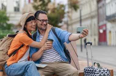 Smiling couple taking selfie while sitting outdoors together