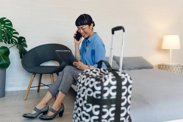 Sandalyede oturan kadın akıllı telefon ve tablet kullanıyor.