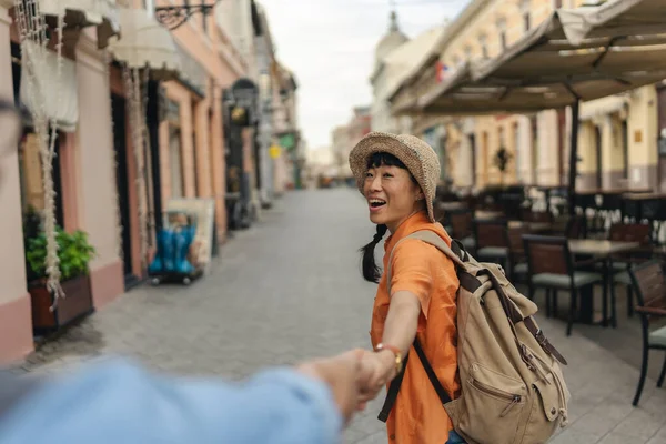 Smiling woman wearing hat holding hand while walking outdoors street