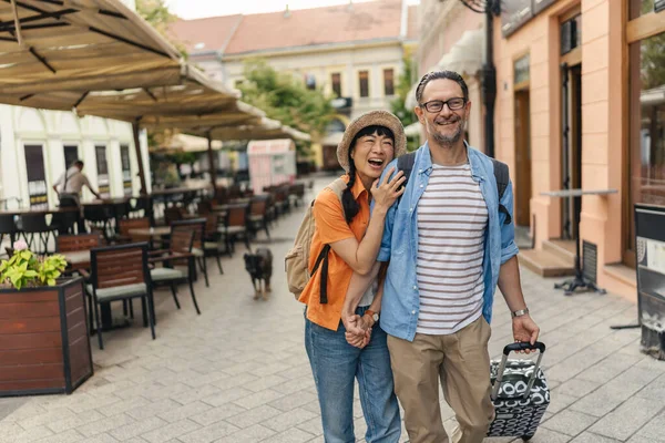 Happy couple walking outdoors holding hands near outdoor cafe
