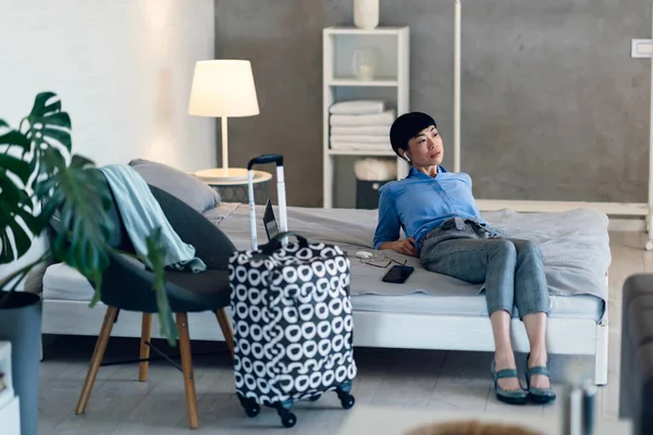 İş kadını modern odadaki bavulun yanında dinleniyor.