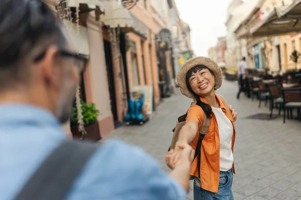 Smiling woman holding hand walking along sunny city street