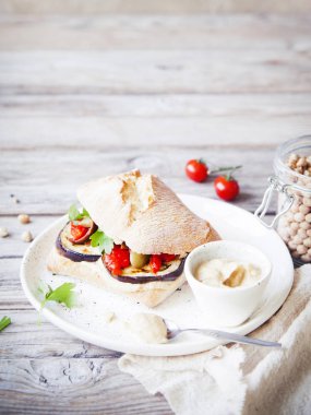 Humus, pişmiş kırmızı biber, zeytin ve rustik ahşap arka plan üzerinde ızgara patlıcan ile sağlıklı vejetaryen sandviç. Tonda.