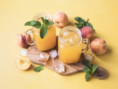 Buz ve nane sarı zemin üzerine taze şeftali ile bir tepsi üzerinde mason kavanoz soğuk yaz şeftali içeceği. Kopya alanı. 