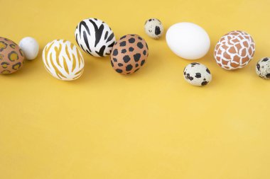 Sarı arka planda Paskalya yumurtaları boyandı. Yaratıcı hayvan deseni.