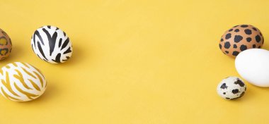 Sarı arka planda Paskalya yumurtaları boyandı. Yaratıcı hayvan deseni.