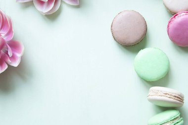 Pastel yeşil arka planda renkli makarna veya makarna kek ve lale.