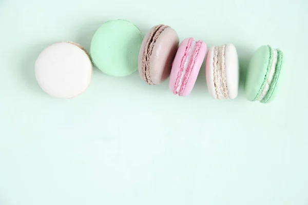 Pasteles coloridos macaron o macaroon sobre fondo verde pastel . —  Fotos de Stock