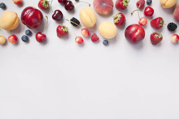 Variety of fresh juicy berries and fruits on grey background. 