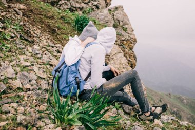 bir dağ uçurumun üzerinde oturan aşık çift