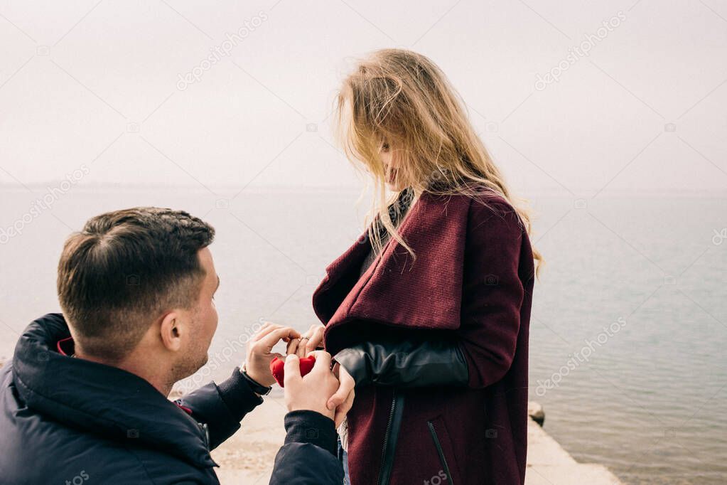 guy makes an offer to a girl in nature by the water