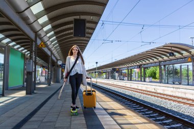 bir genç kız bir quitar ve kaykay üzerinde Tren İstasyonu ile portresi