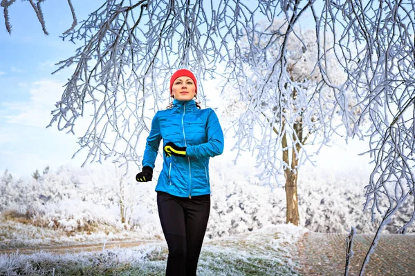 冬の森をジョギングする若い女性 — ストック写真