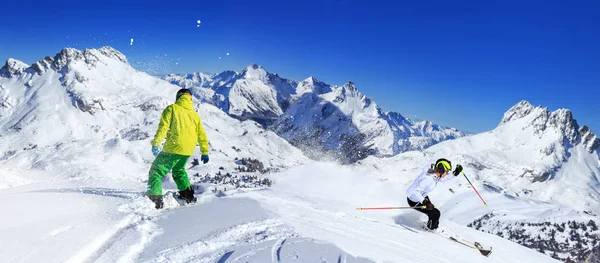 A snowboarder and ski driver on the piste in Alps in Austria