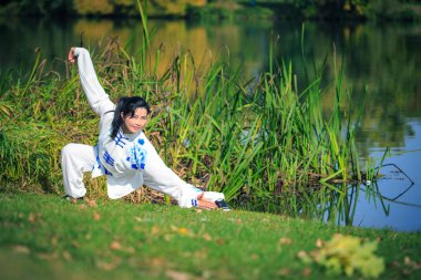 Genç kadın bir gölde taichi ya da qi gong egzersiz yaparak