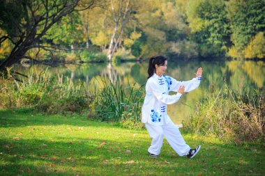 Genç kadın bir gölde taichi ya da qi gong egzersiz yaparak