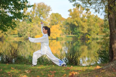 Genç kadın bir gölde taichi ya da qi gong egzersiz yaparak