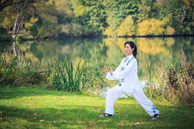 Genç kadın bir gölde taichi ya da qi gong egzersiz yaparak