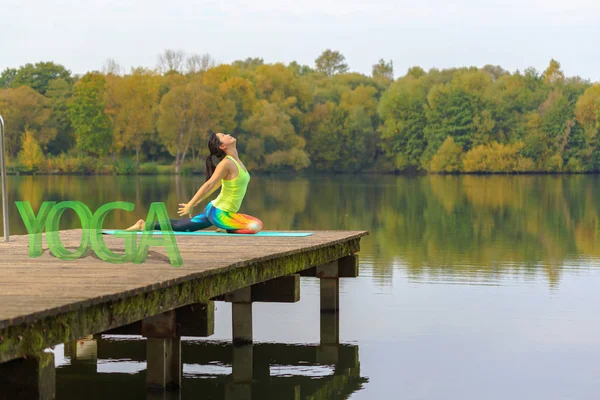 湖でのヨガの練習を行う若い女性 — ストック写真