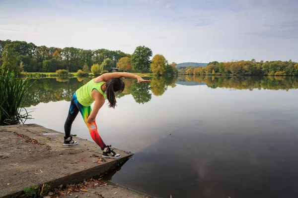 若い女性の湖でジョギング ストレッチ — ストック写真
