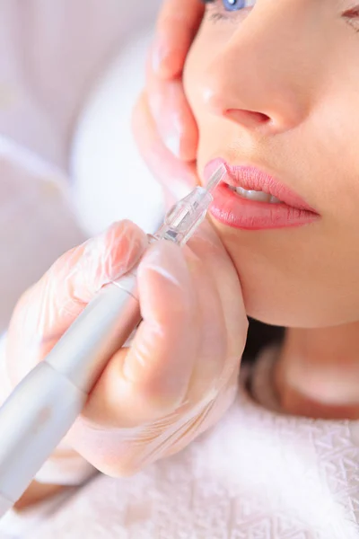 closeup of a female face by receiving of permanent makeup treatment at the beauty salon