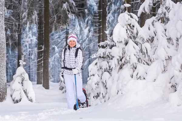 年轻女子在白雪皑皑的森林里徒步旅行 — 图库照片