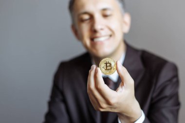 Mutlu genç iş adamı bir altın bitcoin tutarak. Sığ derinlik-in tarla. Bitcoin üzerinde odaklanmak.