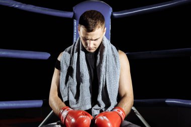 Sıradaki maç için antrenman yaparken ringin köşesindeki iplerde dinlenen kaslı profesyonel boksör.