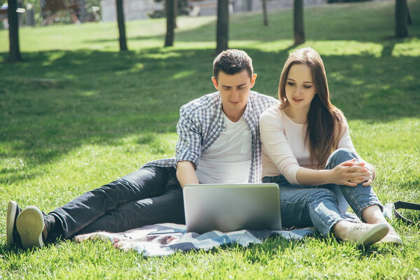 Молодая милая пара с ноутбуком в парке в солнечный день
.