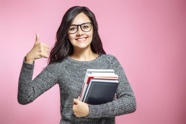 Bir pembe başparmak gösterilmesini kitapları ile gülümseyen kız.