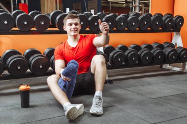 Mutlu çekici adam bir egzersiz yaptıktan sonra dinlenme ve spor salonunda parmağını gösterir