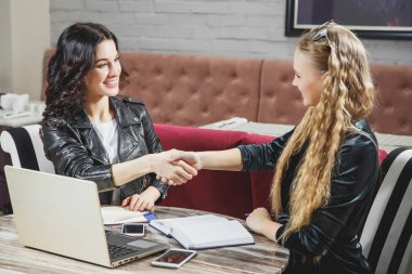 El sıkışan ve birbirine iş toplantısında otururken gülümseme ile bakarak iki güzel kadın