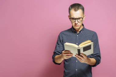 Pembe bir arka plan üzerine bir kitap okurken erkek