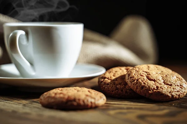 Hot coffee and cookies on a dark background.