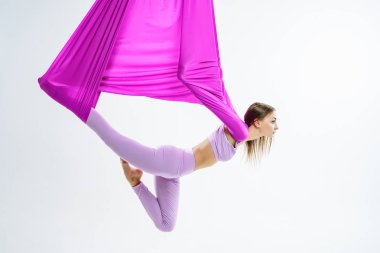 Genç güzel yogi kadının mor hamakta hava yoga pratik yapması