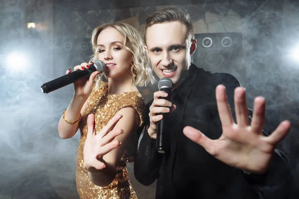 Young attractive couple singing against the smoke in a dark room