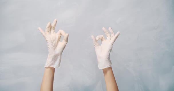 Close Van Vrouwelijke Handen Beschermende Handschoenen Tonen Gebaar Grijze Achtergrond — Stockvideo