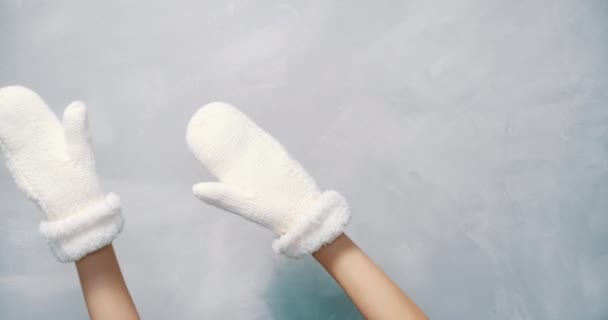 白い毛糸で女性の手を閉じる灰色の背景に左右に手を振ってミトン — ストック動画