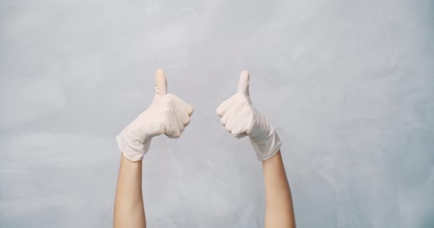 グレーの背景に親指を示す保護手袋で女性の手のクローズアップ スペースのコピー — ストック動画